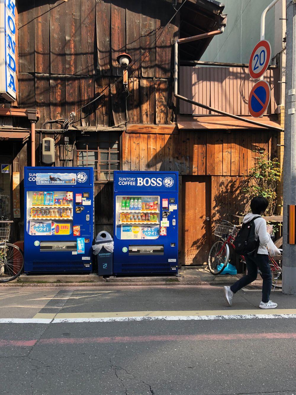 Two slim blue vending machines on a street corner