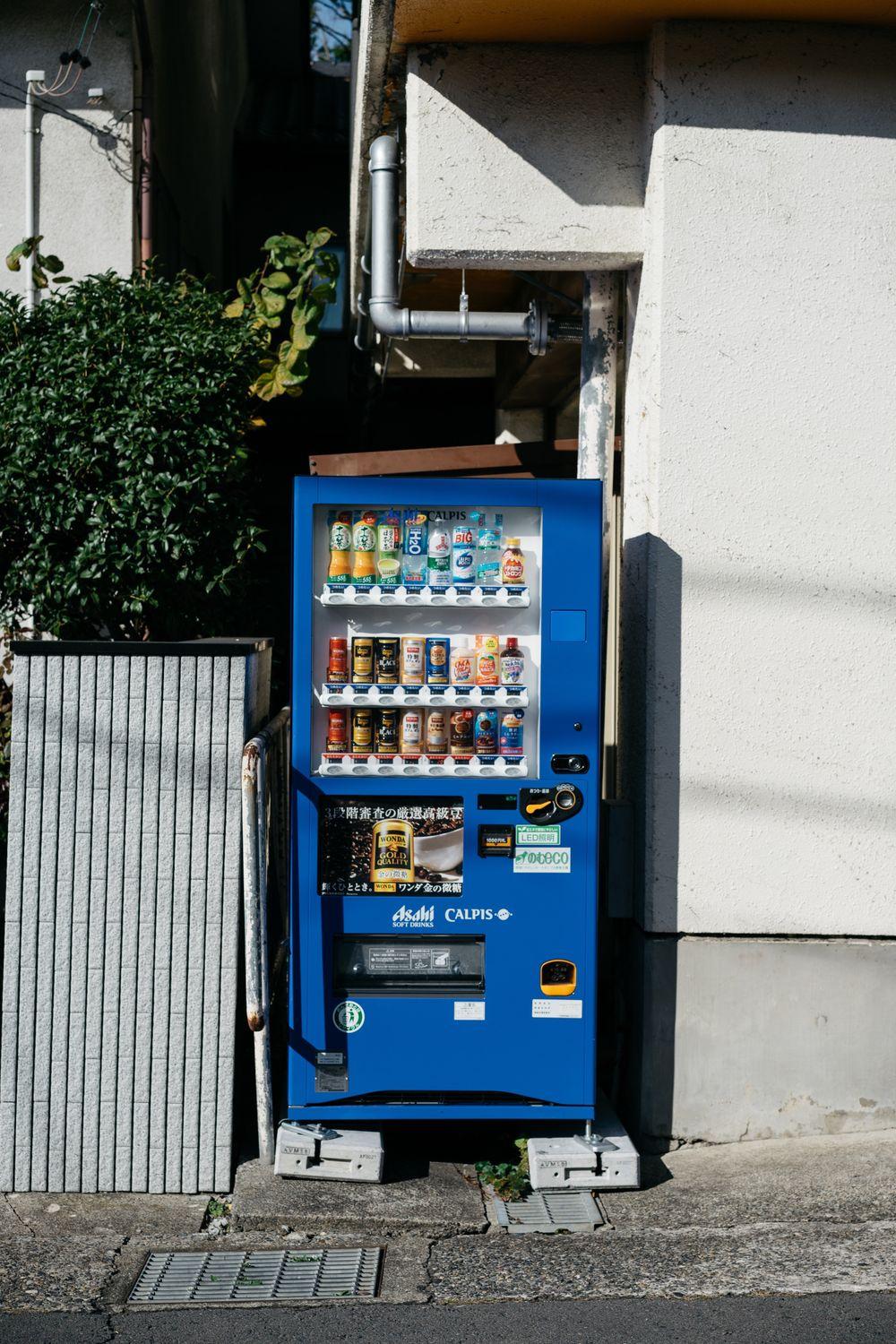Blue combo vending machine with drinks and snacks beside a building